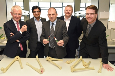 five men stand in front of an table with various bones on it