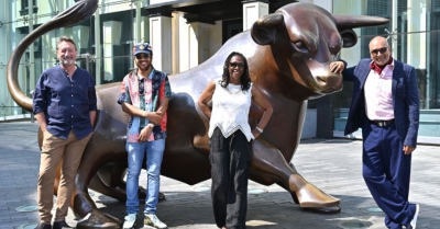 four people stand in front of Birmingham's bullring bull