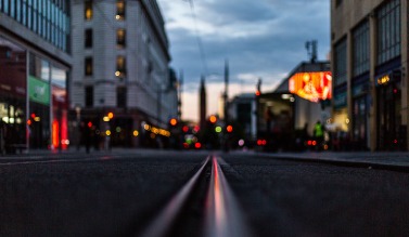A shot taken from ground level of a road stretching on and blurred lights in the background