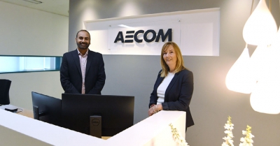 two people smile at the camera from the reception area at AECOM