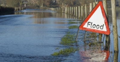 A flooded road with a food warning sign