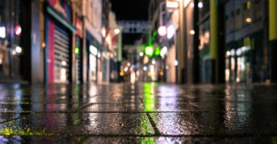 A damp pavement with city lights reflections glittering