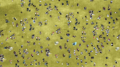 A view from above of people sat on the grass in a green field