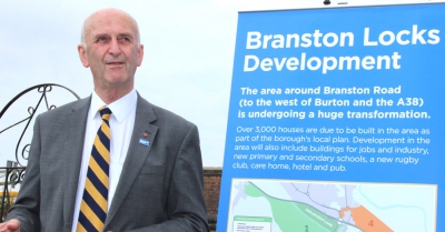 A man stands beside a sign for the branston locks development