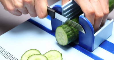 a cucumber being sliced whilst held in a plastic holder