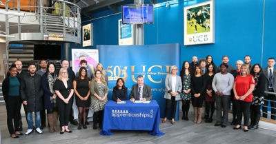 A large group of people stand around a table which says apprenticeships